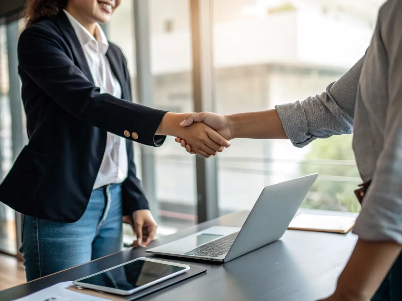 A professional photograph of a handshake between two individuals in a modern office setting, with legal documents visible in the background, symbolizing coordination with qualified intermediaries.